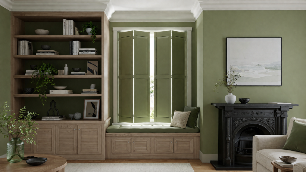 A styled interior room featuring a built-in wooden bookcase on the left, a green bay window with open folding shutters and a cushioned seat in the center, and a black fireplace with wall art on the right.